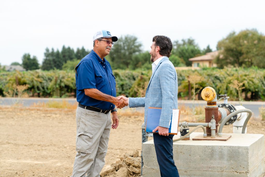 Adviser shaking hands with a farm family in the field